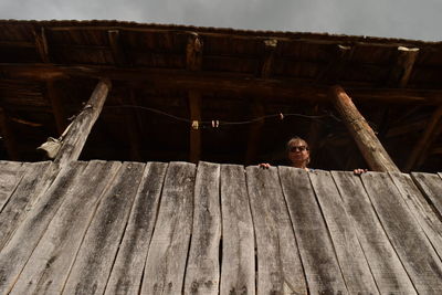 Portrait of man standing on wood against sky