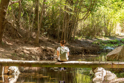 Woman sitting by lake in forest