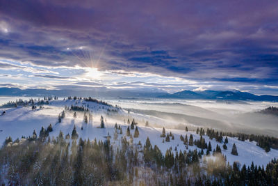 Scenic view of snow covered landscape against sky during sunset