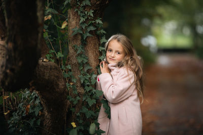 Young woman standing against trees