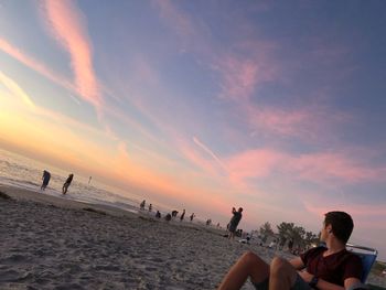 People on beach against sky during sunset