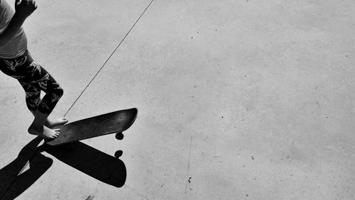 Low section of girl standing with skateboard on footpath