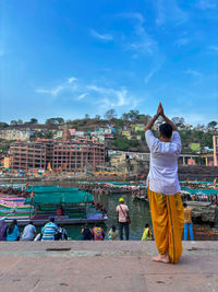Rear view of young woman standing at beach against sky