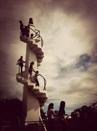 Low angle view of people against cloudy sky