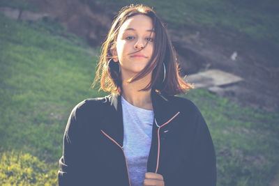 Portrait of beautiful young woman standing on field