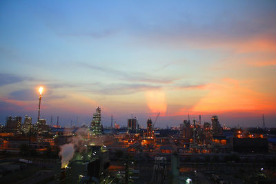 Illuminated cityscape against sky during sunset