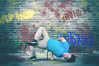 Man relaxing on seat against brick wall