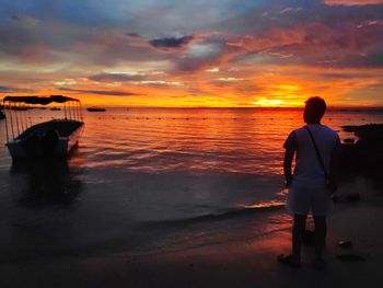 Men standing on beach against sky during sunset