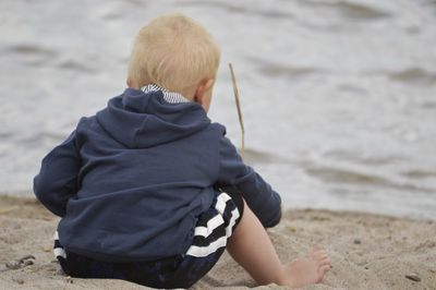 Rear view of boy sitting at beach