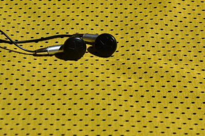 High angle view of earphones on yellow fabric