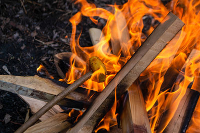 A fire burns in a campfire with a red fire in the background.