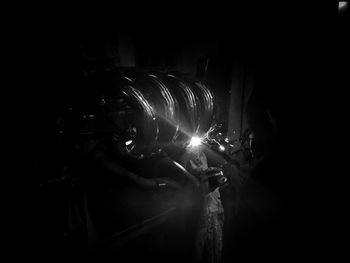 Man holding illuminated fire in dark room