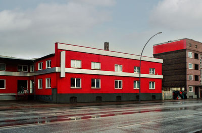 Red building by road against sky in city