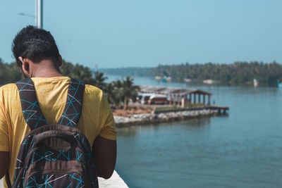 Rear view of man by river against clear sky