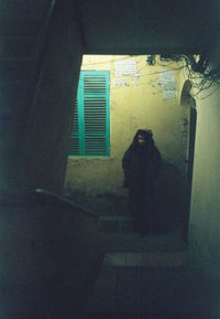 Man standing by window of building at night