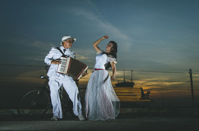 Man playing musical instrument standing by dancer