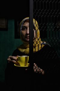 Close-up of young woman holding coffee cup at home