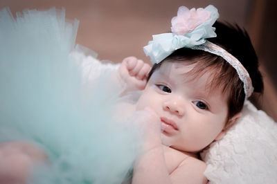 Close-up portrait of cute baby girl lying on bed