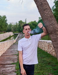 Portrait of young man standing against trees