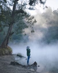 A woman enjoys the beauty of the lake shrouded in mist