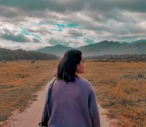 Rear view of man standing on landscape against sky