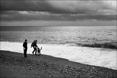 Rear view of man and woman with dog at beach