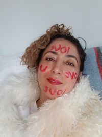 Portrait of woman lying on sofa with text on face