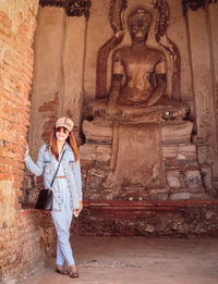 Full length of young woman standing against wall