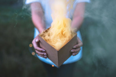 Midsection of woman holding burning box