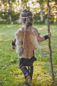 Cute baby dressed in the clothes of primitive people with combat staff