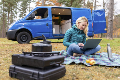 Man using mobile phone while sitting on land