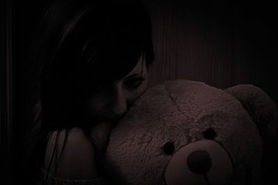 Portrait of young woman with toy on bed at home