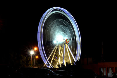 Low angle view of illuminated ferris wheel spinning at night