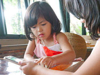 Young woman using mobile phone while sitting at home