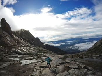 Hiker standing on mountain against sky