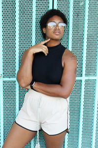 Portrait of young woman looking away while standing against wall