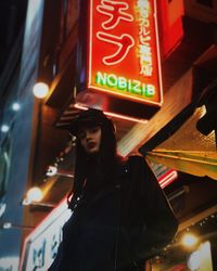 Low angle view of woman standing against illuminated light at night