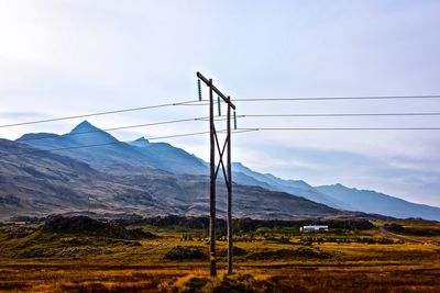 Electricity pylon on field against sky