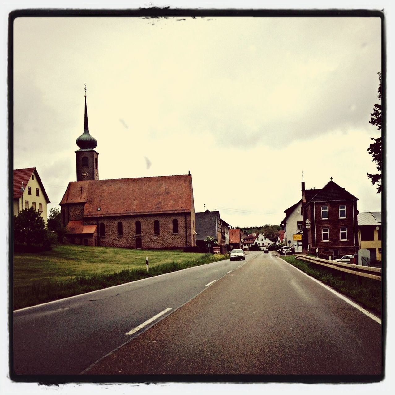 building exterior, architecture, the way forward, transfer print, built structure, road, sky, transportation, auto post production filter, street, diminishing perspective, road marking, vanishing point, car, cloud - sky, church, empty, city, cloud, outdoors