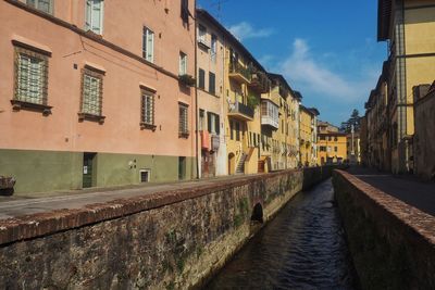 Canal amidst buildings in city against sky