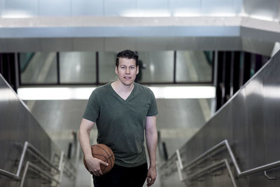 High angle portrait of young man with basketball moving up on steps