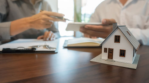 Cropped hands of real estate agent sitting with customer in office
