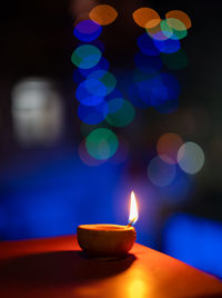 Close-up of illuminated candles burning against blurred background