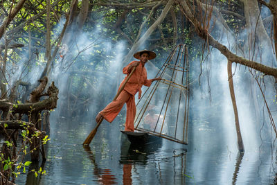 Man in river amidst trees in forest