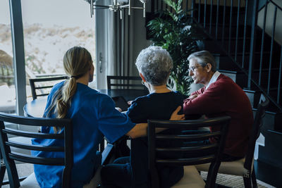 Senior couple and home caregiver sitting at dining table