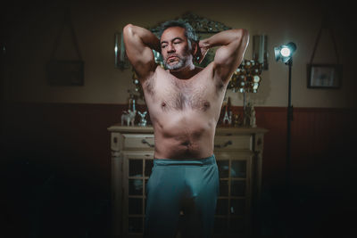Full length of shirtless young man standing against wall
