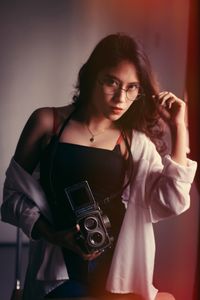 Portrait of young woman with camera sitting at home