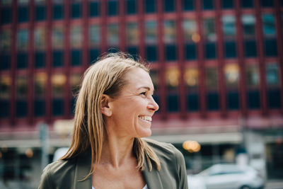 Portrait of a smiling young woman looking away outdoors