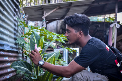 Side view of young man looking at plants