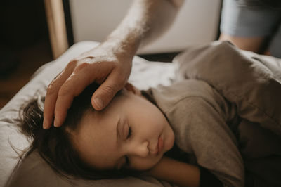 Father caressing son sleeping on bed at home